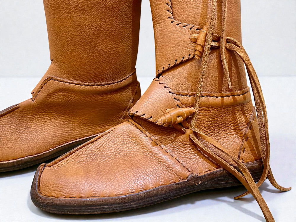 Handmade medieval leather boots with wrap laces, visible stitching, and full-grain texture for LARP or SCA reenactment.