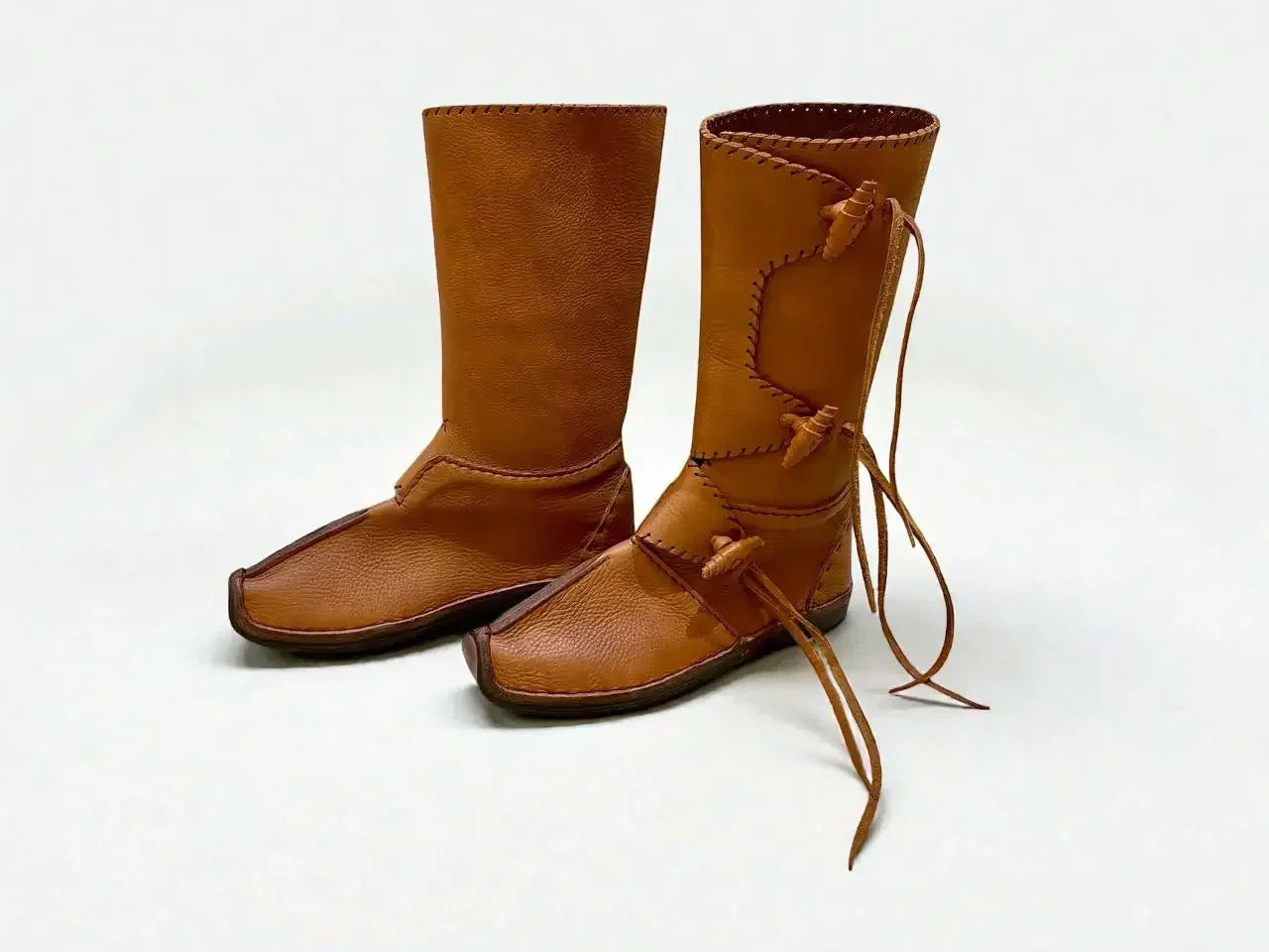 Handmade medieval leather boots with wrap laces and visible stitching, crafted from full-grain leather for LARP or SCA reenactment.